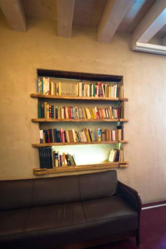 a shelf of books on a wall with a couch at Hotel Remàt in Garda