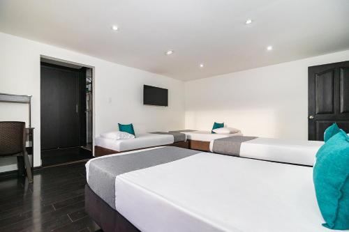 two beds in a hotel room with a tv at Ayenda Puerto Madero Boutique in Chía