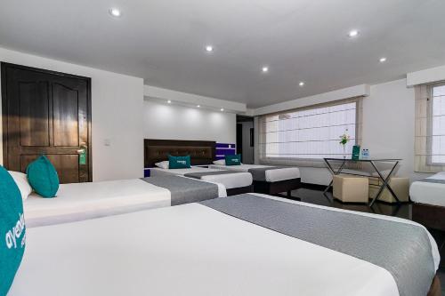 a hotel room with three beds and a table at Ayenda Puerto Madero Boutique in Chía
