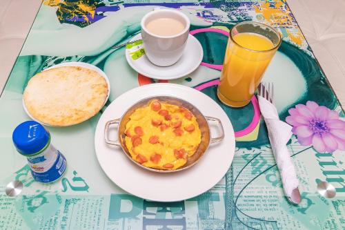 a table with a plate of food and a glass of orange juice at Ayenda Puerto Madero Boutique in Chía
