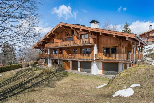 Cette grande maison en bois dispose d'un balcon sur une colline. dans l'établissement L'Écrin Alpin - Welkeys, à Megève
