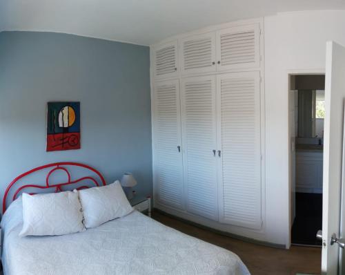 1 dormitorio con cama blanca y pared azul en Edificio Torre Antares Apt. 704, en Punta del Este