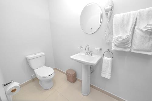 a white bathroom with a toilet and a sink at Árbol Suites in Tijuana
