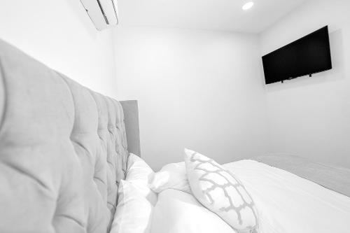 a white bed with a television on a wall at Árbol Suites in Tijuana