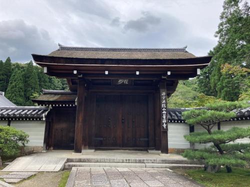 a wooden gate to a building in a garden at HOTEL TAVINOS Kyoto in Kyoto