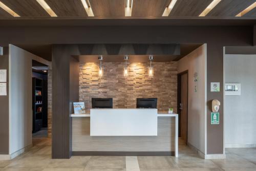 a lobby with a white counter and a brick wall at Wingate by Wyndham Kanata West Ottawa in Ottawa