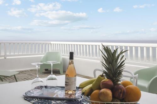 einen Tisch mit einem Tablett mit Obst und Weinflaschen in der Unterkunft L'appartement Océane - Welkeys in Capbreton