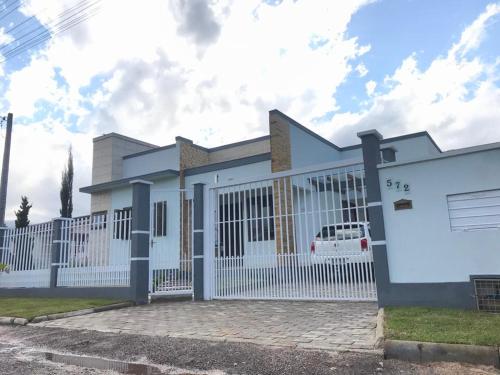 ein Haus mit einem weißen Zaun in der Unterkunft Casa Aconchego dos Canyons in Praia Grande