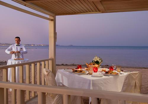 a man standing in front of a table on the beach at Premier Le Reve Hotel & Spa Sahl Hasheesh - Adults Only 16 Years Plus in Hurghada