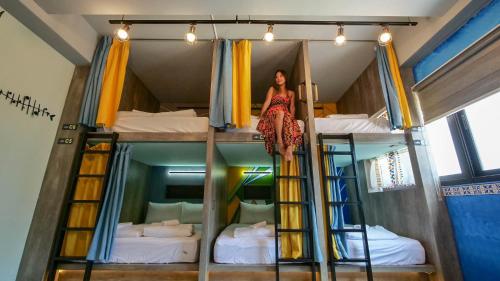 a woman in a dress is standing on a bunk bed at 澎湖 玩聚背包民宿 in Huxi