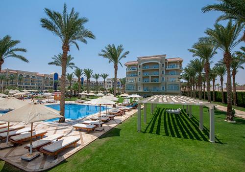 a resort with a pool and lounge chairs and palm trees at Premier Le Reve Hotel & Spa Sahl Hasheesh - Adults Only 16 Years Plus in Hurghada