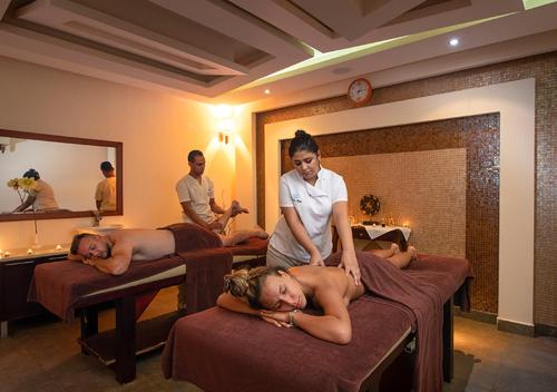 a woman standing on two beds with two people laying on them at Premier Le Reve Hotel & Spa Sahl Hasheesh - Adults Only 16 Years Plus in Hurghada