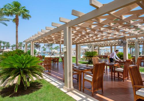 a patio with tables and chairs under a pergola at Premier Le Reve Hotel & Spa Sahl Hasheesh - Adults Only 16 Years Plus in Hurghada