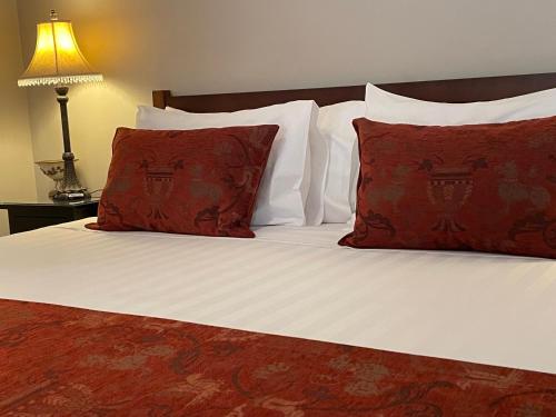 a bed with white sheets and red pillows at Burradoo Studio in Leura