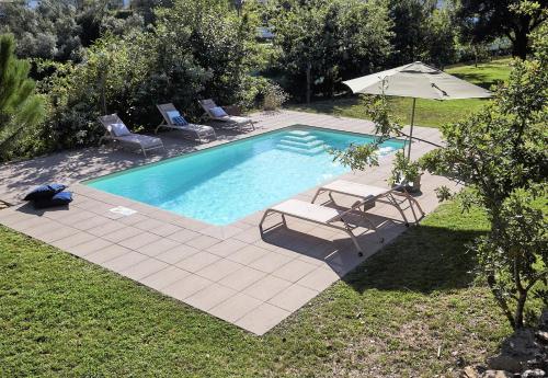 a swimming pool with two chairs and an umbrella at Casa da Oliveira in Caminha