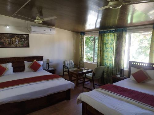 a hotel room with two beds and a table and chairs at Rose Cottage - A Heritage Retreat in Mount Ābu
