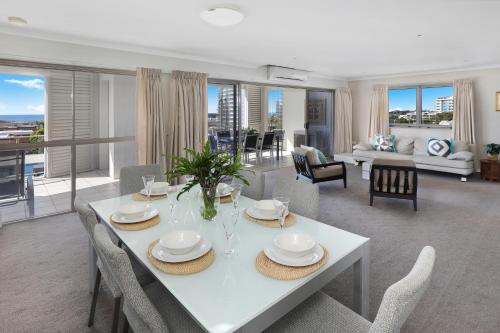 a dining room and living room with a white table and chairs at Rovera Apartments in Maroochydore