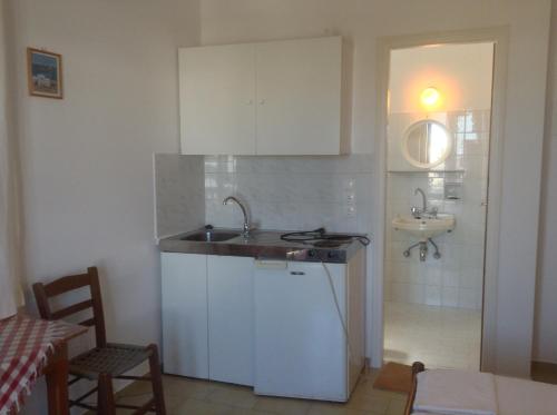 a kitchen with white cabinets and a sink and a bathroom at Rania Apartments in Antiparos Town