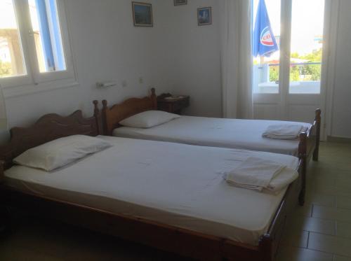 two twin beds in a room with two windows at Rania Apartments in Antiparos Town