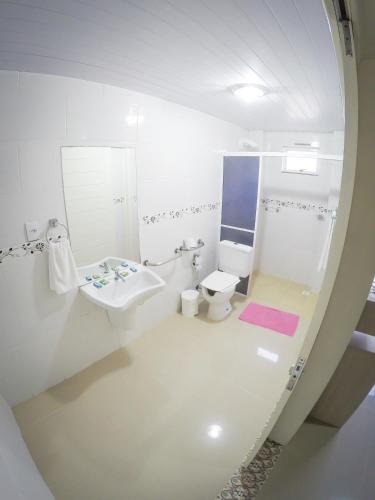 a white bathroom with a sink and a toilet at Hotel Guerra - Pousada Montebelo in Jaguaruna
