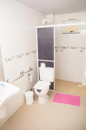 a white bathroom with a toilet and a sink at Hotel Guerra - Pousada Montebelo in Jaguaruna
