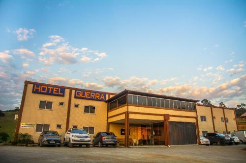 a hotel with cars parked in a parking lot at Hotel Guerra - Pousada Montebelo in Jaguaruna