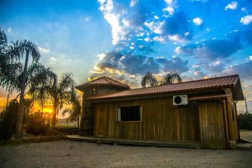 a wooden house with a sunset in the background at Hotel Guerra - Pousada Montebelo in Jaguaruna