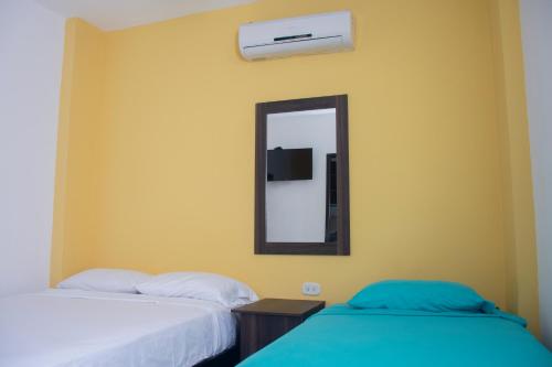 a bedroom with two beds and a mirror at Hotel Gixael in Santa Marta
