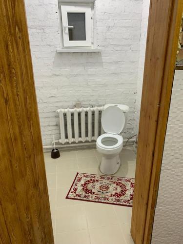 a white bathroom with a toilet and a window at Kolsay Aisha in Saty