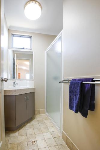 a bathroom with a shower and a sink and a mirror at Kalbarri Tudor Holiday Park in Kalbarri