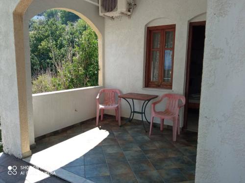a porch with two chairs and a table and a window at Nikos Studios in Gialiskari
