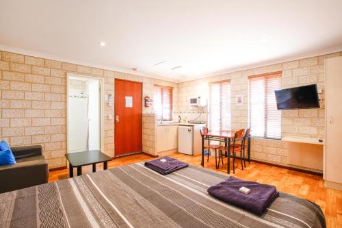 a bedroom with a large bed and a kitchen at Kalbarri Tudor Holiday Park in Kalbarri