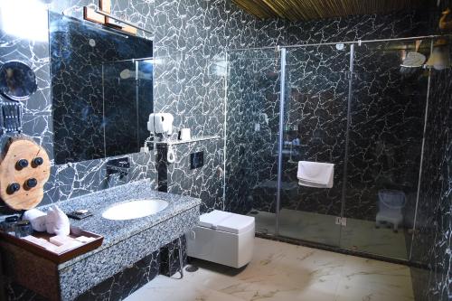 W łazience znajduje się szklana kabina prysznicowa i umywalka. w obiekcie Puratan Qila w mieście Sawai Madhopur