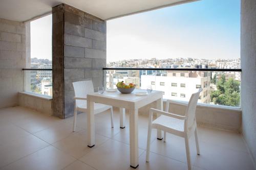a white table and chairs in a room with a large window at Triple A Hotel Suites in Amman