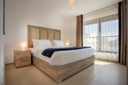 a bedroom with a large bed and a large window at Triple A Hotel Suites in Amman