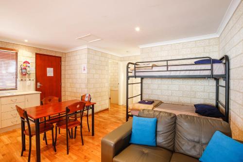 a room with a couch a table and a bunk bed at Kalbarri Tudor Holiday Park in Kalbarri