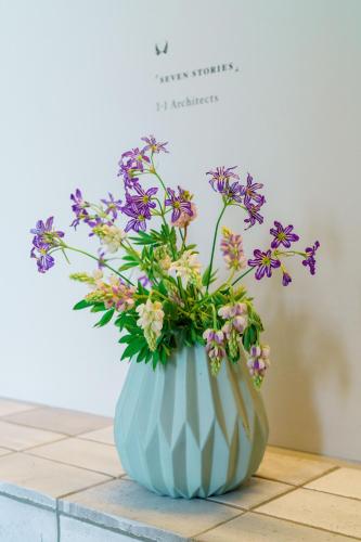 a blue vase filled with purple and white flowers at Seven Stories in Nagoya