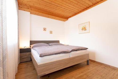 sypialnia z łóżkiem i drewnianym sufitem w obiekcie Appartements Wagnerhaus w mieście Maria Alm am Steinernen Meer