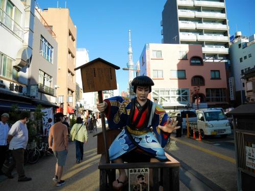 a statue of a man sitting on a box on a street at HOTEL TAVINOS Asakusa in Tokyo