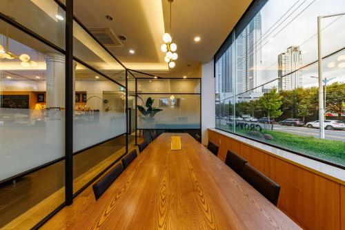 a long wooden table in a building with windows at Crown Hotel Changwon in Changwon