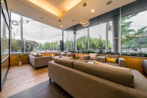 a large room with couches and chairs and windows at Crown Hotel Changwon in Changwon