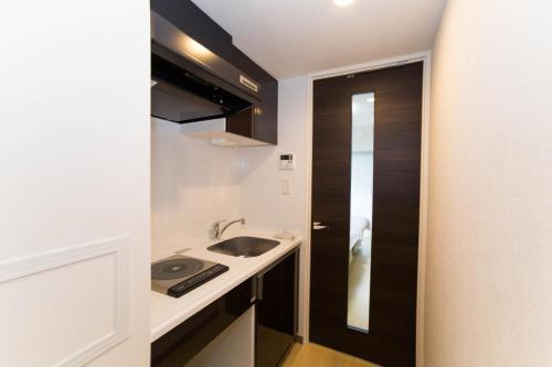 a small kitchen with a sink and a black door at Universal Haneda in Tokyo