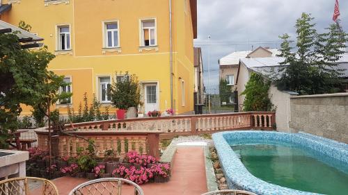 basen przed żółtym budynkiem w obiekcie Penzion Duong Apartments w Karlowych Warach