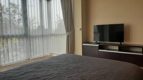 - une chambre avec un lit et une télévision à écran plat dans l'établissement Jaukūs apartamentai, à Šiauliai