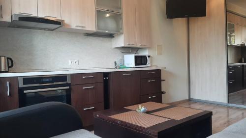 eine Küche mit Holzschränken und einem Tisch darin in der Unterkunft Jaukūs apartamentai in Šiauliai