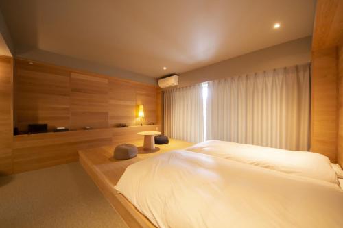 a bedroom with a large white bed and a tub at Seven Stories in Nagoya