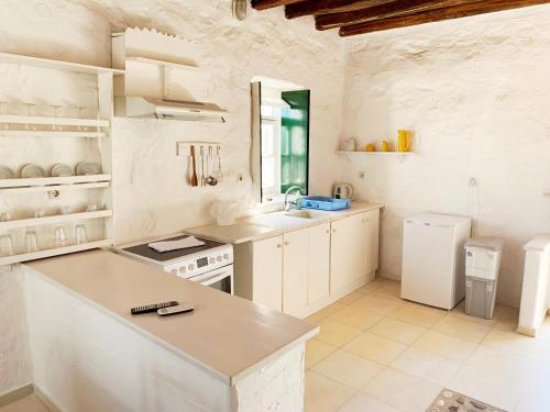 a white kitchen with a sink and a refrigerator at Anezina Village in Drios