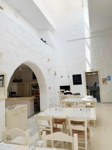 a white room with tables and chairs and a kitchen at Anezina Village in Drios