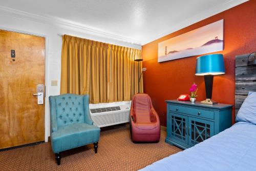 um quarto de hotel com uma cama e uma cadeira e uma janela em Americana Inn Motel em South San Francisco