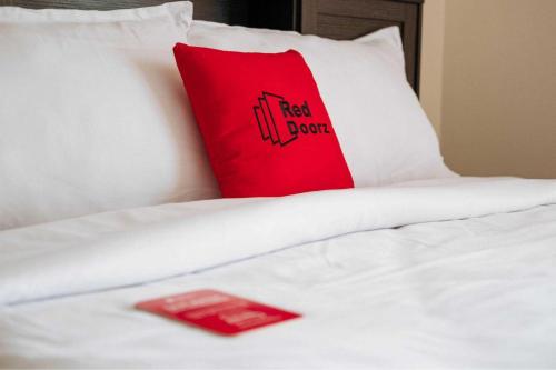 a red pillow sitting on top of a white bed at RedDoorz Syariah near RS Harapan Bunda Banda Aceh in Geutieue